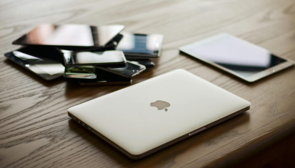 Current image: A variety of modern electronic gadgets, including a laptop and smartphones, on a wooden table.